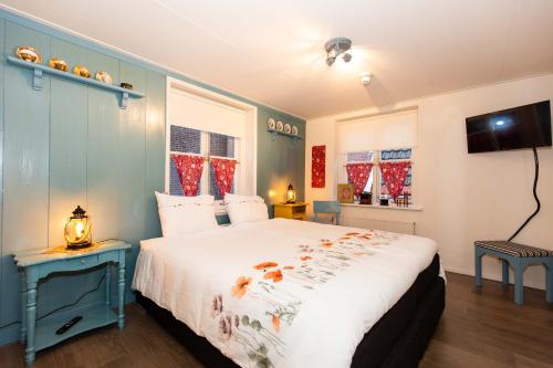 a bedroom with a large bed and a tv at Bed and Breakfast De Pepersteeg in Marken