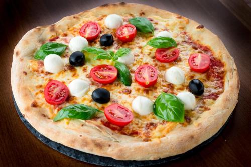 a pizza with tomatoes and olives on a table at Mon Repos in Lido di Jesolo