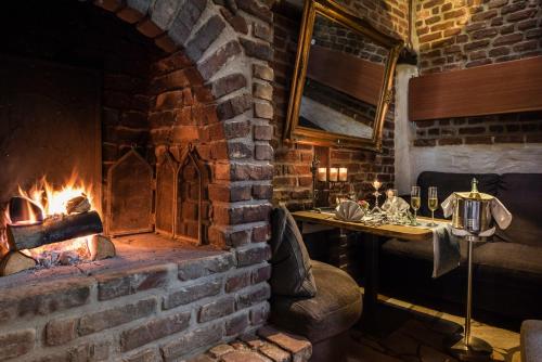 a brick room with a fireplace and a table at Hotel Land Gut Höhne in Mettmann