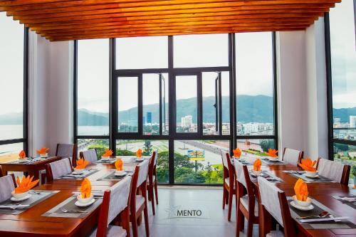 a dining room with long tables and chairs and a large window at MENTO HOTEL QUY NHƠN in Quy Nhon