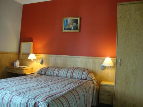 a hotel room with a bed and a red wall at Clifford House B & B in Rosslare