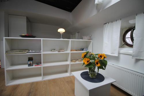 Zimmer mit weißen Regalen und einer Blumenvase auf dem Tisch in der Unterkunft studio Vincent van Gogh in Amsterdam
