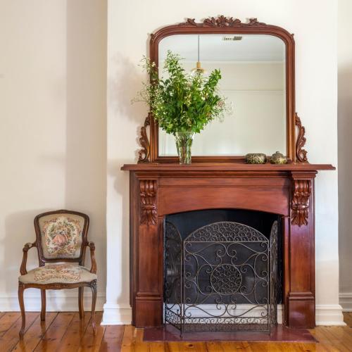 a mirror on top of a fireplace with a chair at Barossa Shiraz Estate in Lyndoch