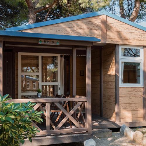 a small wooden cabin with a porch and a door at HolaCamp Sitges Garrofer in Sitges