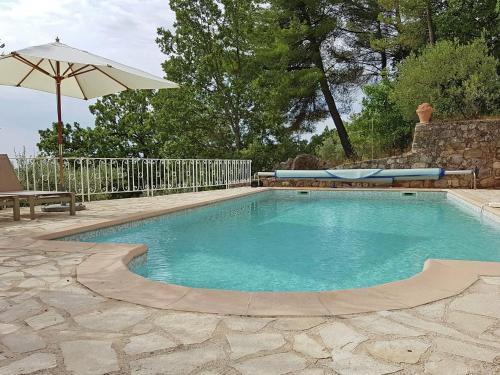 a small swimming pool with an umbrella and a bench at Provencal air conditioned villa in Fayence
