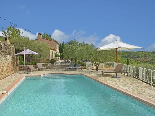 a swimming pool with chairs and an umbrella at Provencal air conditioned villa in Fayence