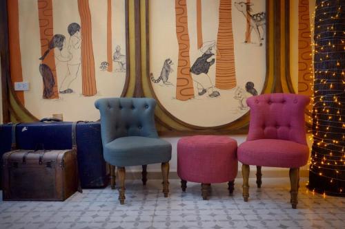 three chairs and a suitcase in a room at Hide and Seek Boutique Hometel in Bangkok