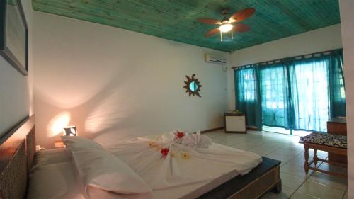 a bedroom with a white bed with a clock on the wall at Takamaka Green Village in Takamaka