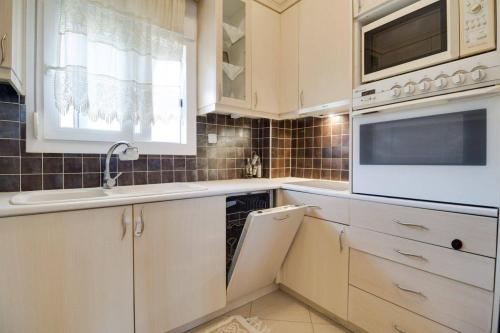 a kitchen with white cabinets and a sink and a microwave at Villa Natali in Flogita