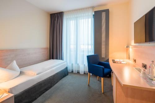 a hotel room with a bed and a chair at IntercityHotel Hamburg Hauptbahnhof in Hamburg