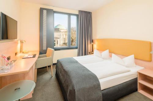 um quarto de hotel com uma cama e uma secretária em IntercityHotel Hamburg Hauptbahnhof em Hamburgo