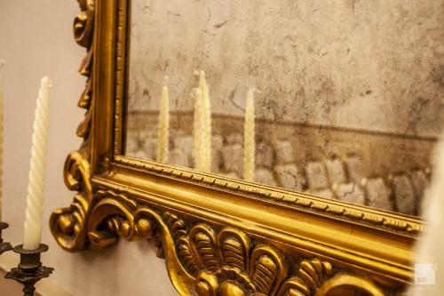 a gold mirror with candles in front of a painting at Hotel Cavour in Bologna