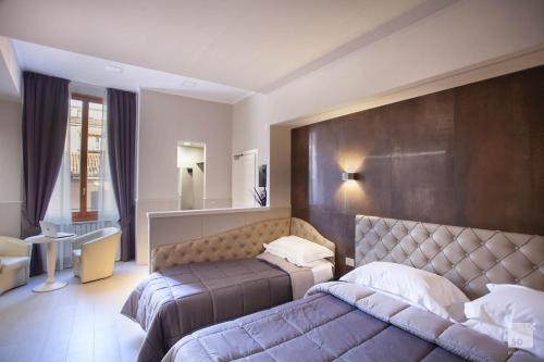 a bedroom with two beds and a large headboard at Hotel Cavour in Bologna