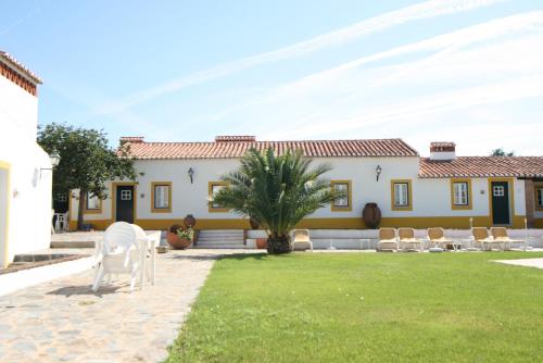 a house with a lawn and chairs in front of it at Quinta do Cabeçote in Cabeço de Vide