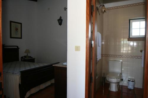 a small bathroom with a toilet and a bed at Quinta do Cabeçote in Cabeço de Vide