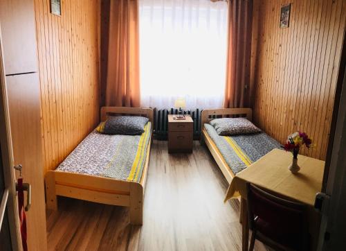 ウイソウィにあるPokoje Gościnneのベッド2台、テーブル、窓が備わる客室です。
