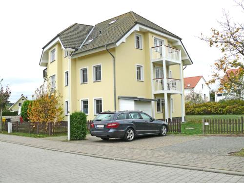 een zwarte auto geparkeerd voor een geel huis bij Bernsteinhaus Wohnung Usedom in Kolpinsee