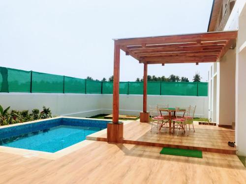 a patio with a table and chairs and a pool at Bleu & Blanc in Puducherry
