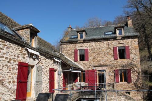 ein altes Backsteingebäude mit roten Rollläden darauf in der Unterkunft Le Moulin de Benechou in Olemps
