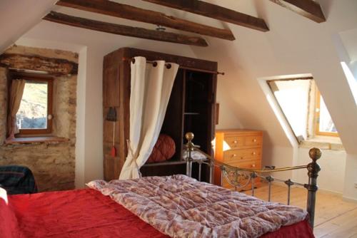 a bedroom with a bed with a red comforter at Le Moulin de Benechou in Olemps