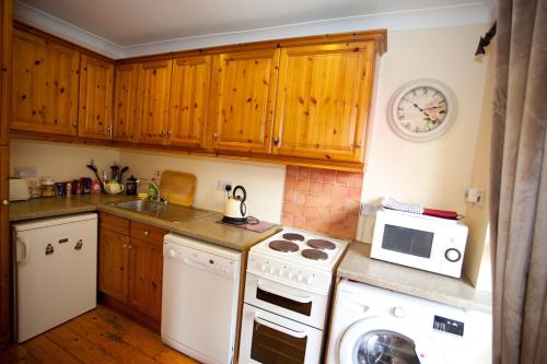 a kitchen with wooden cabinets and a stove and a microwave at Evergreen Bed & Breakfast in Swords