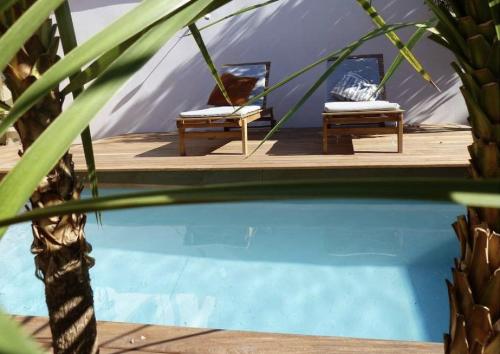 une tente et deux bancs à côté d'une piscine dans l'établissement Le Nid du Héron, maison avec piscine chauffée privative au cœur de Nantes, à Nantes