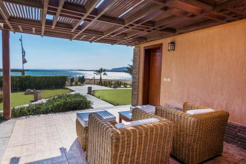 a patio with wicker chairs and a table with a view of the beach at Shams Prestige Abu Soma (Adults Only) in Hurghada