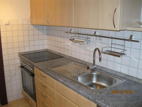 a kitchen with a sink and a tiled wall at Ferienwohnung Anna in Maroldsweisach