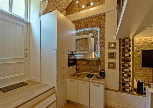 クルジュ・ナポカにあるVinodorum Apartmentsの白いキャビネットとレンガの壁が備わるキッチン