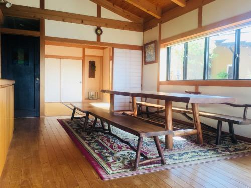 una sala da pranzo con tavolo e panche su un tappeto di Shimanto River House Yuube-Tei a Shimanto