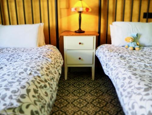 a bedroom with two beds and a teddy bear on a night stand at Privat Hotel Liberty Sitges in Sitges