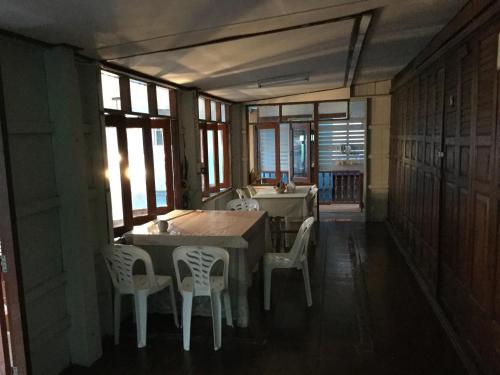 Un comedor con mesa y sillas y ventanas. en Siriwal Guesthouse, en Phra Nakhon Si Ayutthaya