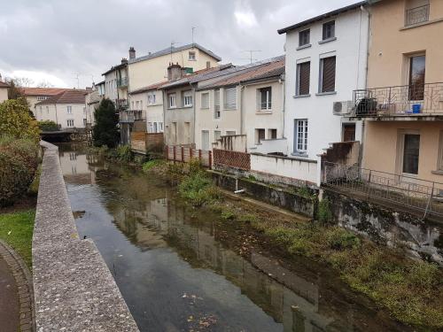 a river in a city with houses and buildings at Chambre dans Grande maison au Coeur de Ville in Verdun