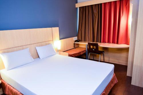 a bedroom with a bed and a chair and a red curtain at Amapá Hotel in Macapá