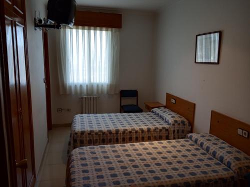 a hotel room with two beds and a television at Hostal Mobydick2 in Ourense