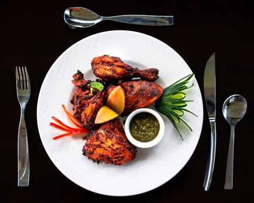 a plate of food with chicken and fruit and sauce at Fun Retreat Resort, Hotel and Ayurveda Spa in Arusha