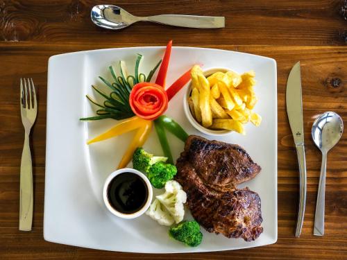 a plate of food with meat and vegetables and fries at Fun Retreat Resort, Hotel and Ayurveda Spa in Arusha