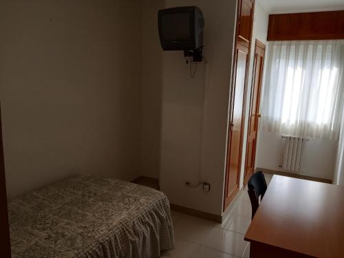 Dormitorio pequeño con cama y TV en Hostal Mobydick2 en Ourense