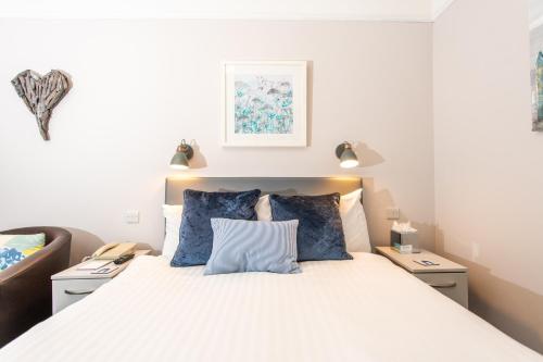 a bedroom with a large bed with blue pillows at Dukes Inn in Sidmouth