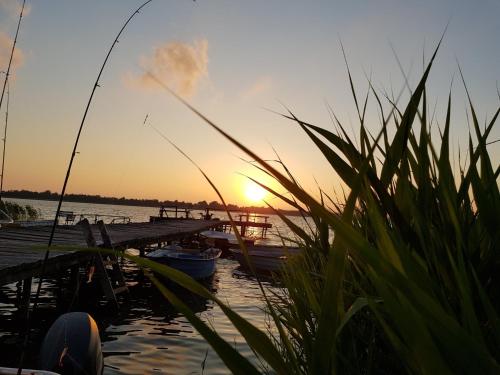 a sunset over a dock with a boat in the water at Villa Maximilian in Srokowo