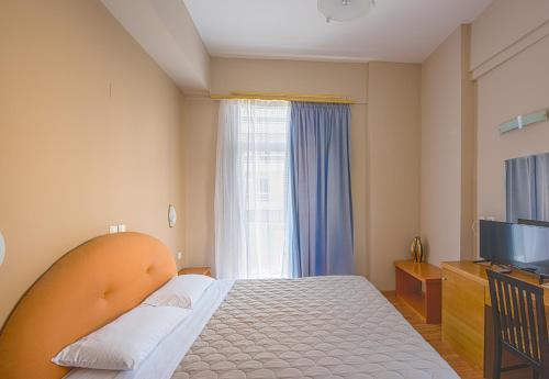 a bedroom with a bed and a tv and a window at Grand Olympic Hotel Loutraki in Loutraki
