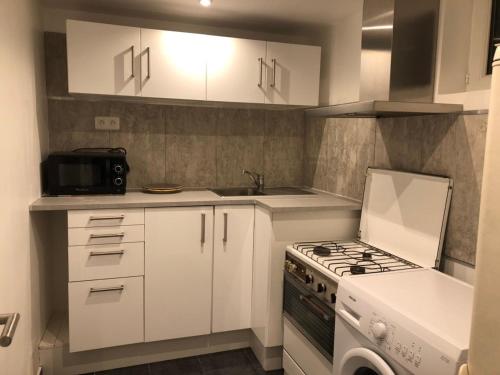 uma cozinha com armários brancos e um forno com placa de fogão em Lalanie em Savigny-sur-Orge