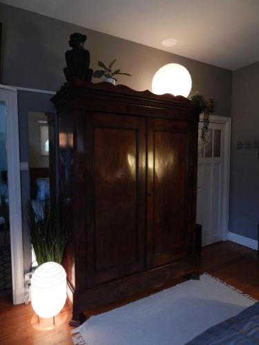 a large wooden cabinet in a living room with a lamp at Les Remparts in Binche