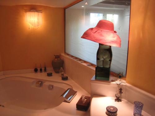 une salle de bain avec un chapeau rouge sur une baignoire dans l'établissement 8 Place du Tertre, à Paris