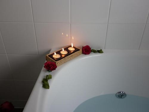 a candle sitting on top of a bath tub with roses at Executive On Fenton in Rotorua