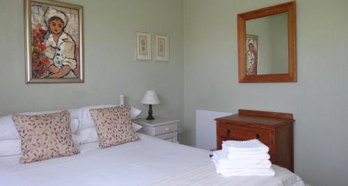 a bedroom with a white bed and a mirror at Braeview Guest House in Hermanus