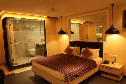 a bedroom with a bed and a bathroom with a shower at Hotel KC Palace in Bhopal