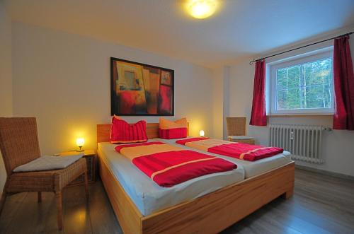 欣特察爾滕的住宿－Ferienhaus Hinterzarten，一间卧室配有一张带红色枕头的大床