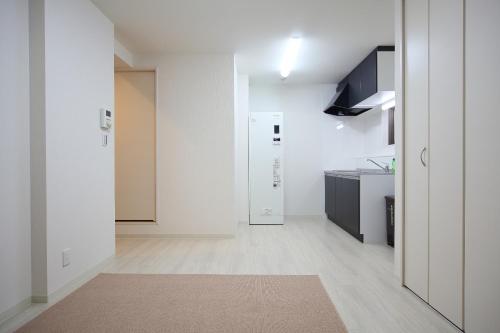 a white room with a kitchen and a hallway at Apartment Heights HANA in Sakai