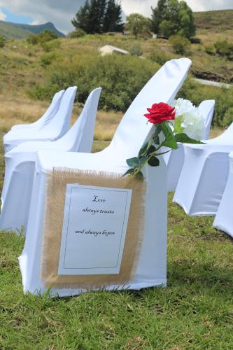 a row of white chairs with a red flower on them at Motebong Lodge in Bokong
